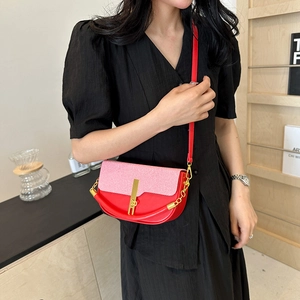 Pink and red spliced half-moon crossbody bag with gold buckle and chain strap shown on model