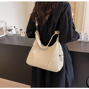 Close-up of a cream white leather tote with lychee texture worn over the shoulder