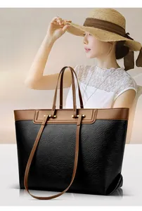 Detail of black lychee grain leather tote bag with brown contrast straps and gold hardware