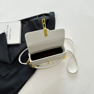 Minimalist white saddle shoulder bag with golden lock on a black suit jacket backdrop