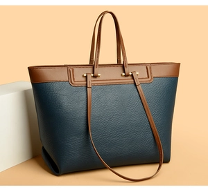 Close-up of contrast tote bag featuring navy pebbled leather and gold hardware