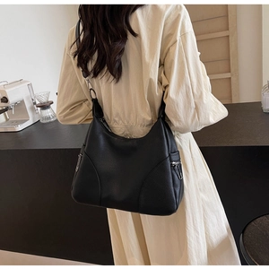 Minimalist black pebbled leather hobo bag with side silver zipper detail shown on a model