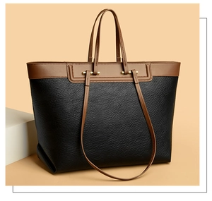 Close-up of litchi texture leather and golden metal hardware on a two-tone tote bag
