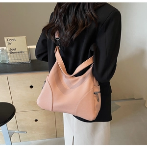 Pink lychee grain leather tote bag with silver zippers shown on a model's shoulder