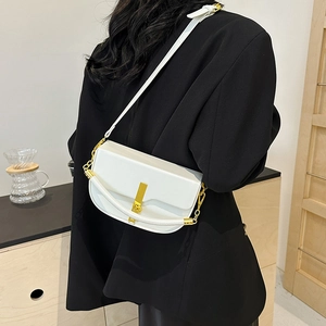 Minimalist white saddle bag with gold metal buckle shown in a stylish crossbody wear