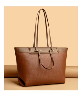 Detail of deep brown lychee grain leather tote bag with elegant gold hardware buckles