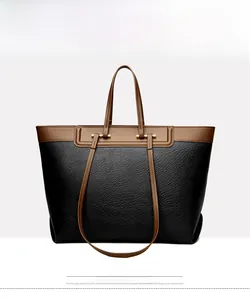 Detail of black lychee leather tote bag with brown contrast handles and golden hardware