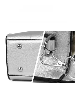 Detail of silver metallic hardware, protective studs and spring buckle on textured tote bag