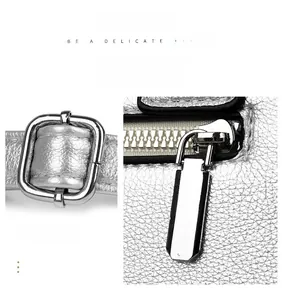 Detail of silver textured leather bag featuring metal adjustment buckle and zipper
