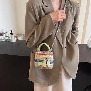 Mini woven box bag with colorful stripes and chain strap worn with a brown blazer
