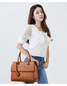 Close-up of brown faux leather tote bag featuring geometric triangular stitching and handle