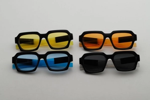 Flat lay macro view of four square sunglasses in yellow, orange, blue, and black colors