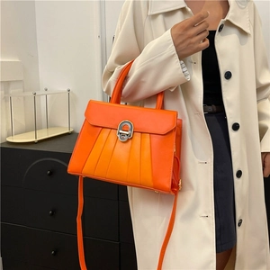 Sac à main chic en similicuir orange avec rabat plissé et boucle métallique porté