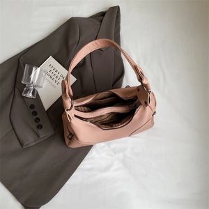 Dusty pink pebbled leather crossbody bag with zipper and striped lining on grey suit