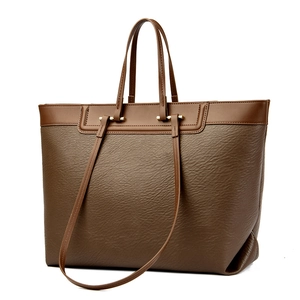 Minimalist large brown tote bag with contrast trim and golden hardware in studio shot