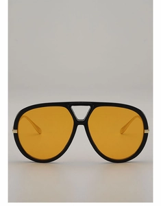 Detail of aviator sunglasses with yellow lenses and black frame with gold hinges