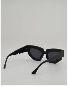 Detail view of matte black irregular cat-eye sunglasses with wide structured temples