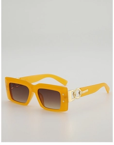 Détail de lunettes de soleil jaunes avec des maillons de chaîne dorés sur les branches