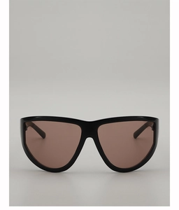 Detail view of glossy black oversized sunglasses frame with translucent brown lenses