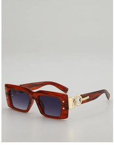 Détail de lunettes de soleil écaillées rouges avec chaîne dorée sur la branche