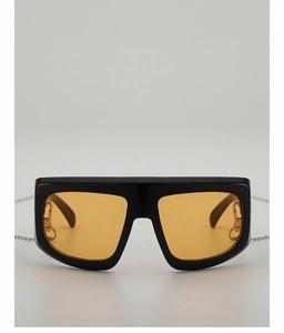 Detail of square Y2K sunglasses with orange lenses, gold hinges and silver chain