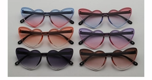 Detailed flat lay of heart-shaped kids sunglasses with various colorful gradient lenses
