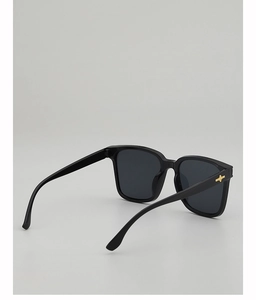 Detail of black square sunglasses featuring a golden cross metal accent on the frame