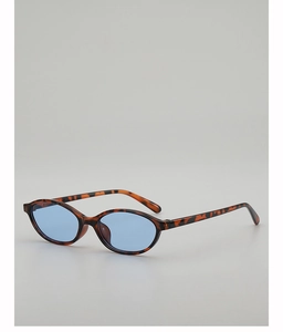 Detail einer Vintage-Sonnenbrille mit ovalem Schildpatt-Rahmen und hellblauen Gläsern