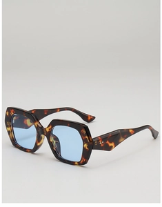 Detail of oversized geometric sunglasses with dark tortoiseshell frames and blue lenses