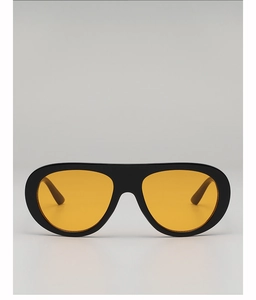 Close-up of thick black aviator sunglasses with vibrant yellow lenses and sleek design