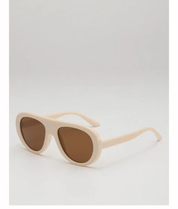 Detail view of the thick cream injection-molded frame and dark brown lenses of pilot sunglasses