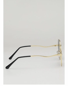 Close-up of golden metal sunglass frame featuring unique wavy temples and black tips