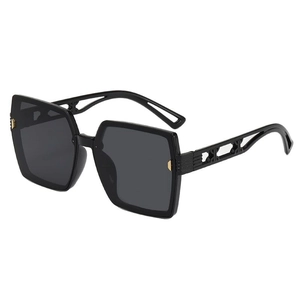 Lunettes de soleil carrées noires avec détails dorés sur les branches sur fond blanc