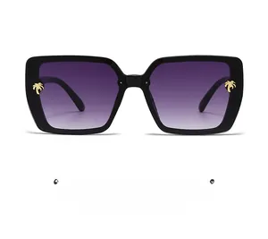 Detail of square black sunglasses with purple gradient lenses and gold palm tree accents