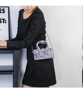 Dettaglio macro della clutch in paillettes argento con manico a specchio a forma di cuore