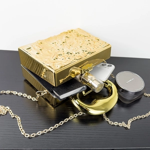 Internal view of gold rectangular box bag showing capacity for phone and cosmetics
