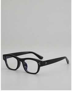 Close-up of black square eyeglass frame with three metal rivets and blue light lens