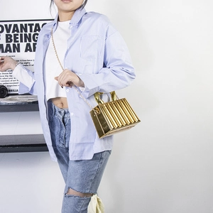 Detail of a structured gold metallic box bag with vertical pleats and chain strap
