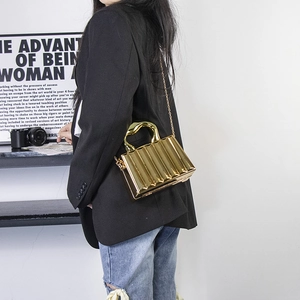 Close-up of golden metallic clutch bag with vertical striped texture and chain strap