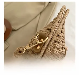 Close-up of premium gold metal hooks and leather straps on a woven crossbody bag