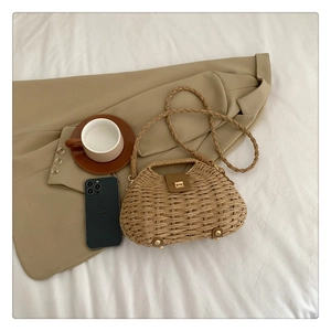 Detailed view of hand-woven straw crossbody bag with leather clasp and metal lock