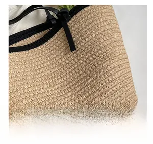 Détail de la texture en paille tressée avec bordure en cuir noir sur un sac fourre-tout