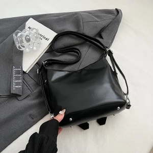 Detail of black PU leather handbag with silver protective metal feet on a gray blazer