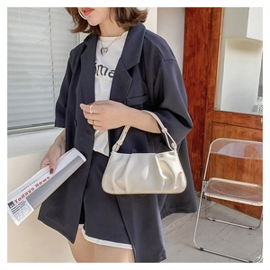 Detail of minimalist off-white pleated PU leather handbag with elegant cloud-style texture