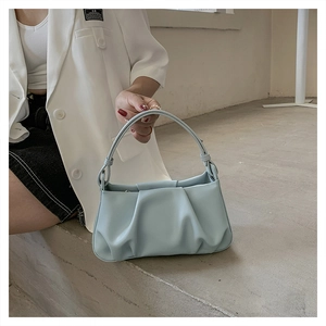 Close-up of light blue pleated handbag with soft leather texture and structured handle