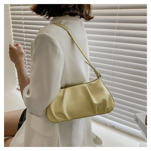 Detail view of the yellow pleated cloud bag texture and sleek leather strap on model