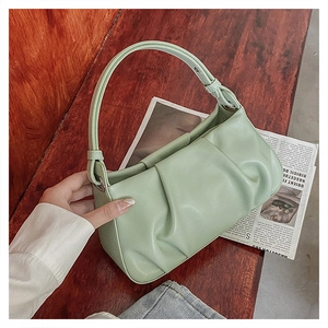 Close-up of mint green ruched handbag with wide handle on a vintage desk