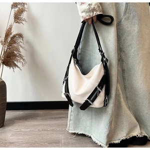 White hobo bag with black straps and metal zippers in a modern minimalist setting