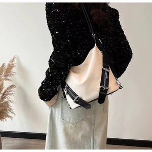 Detail of cream-white crossbody bag showing soft matte texture and metallic buckles