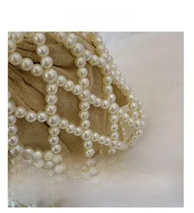 Close-up of handmade beaded evening bag showing white pearls and linen lining texture
